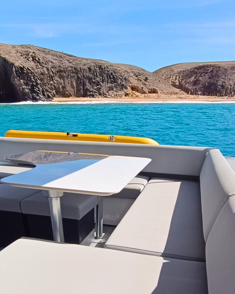 Zona de asientos del yate con las aguas turquesas de Papagayo al fondo.