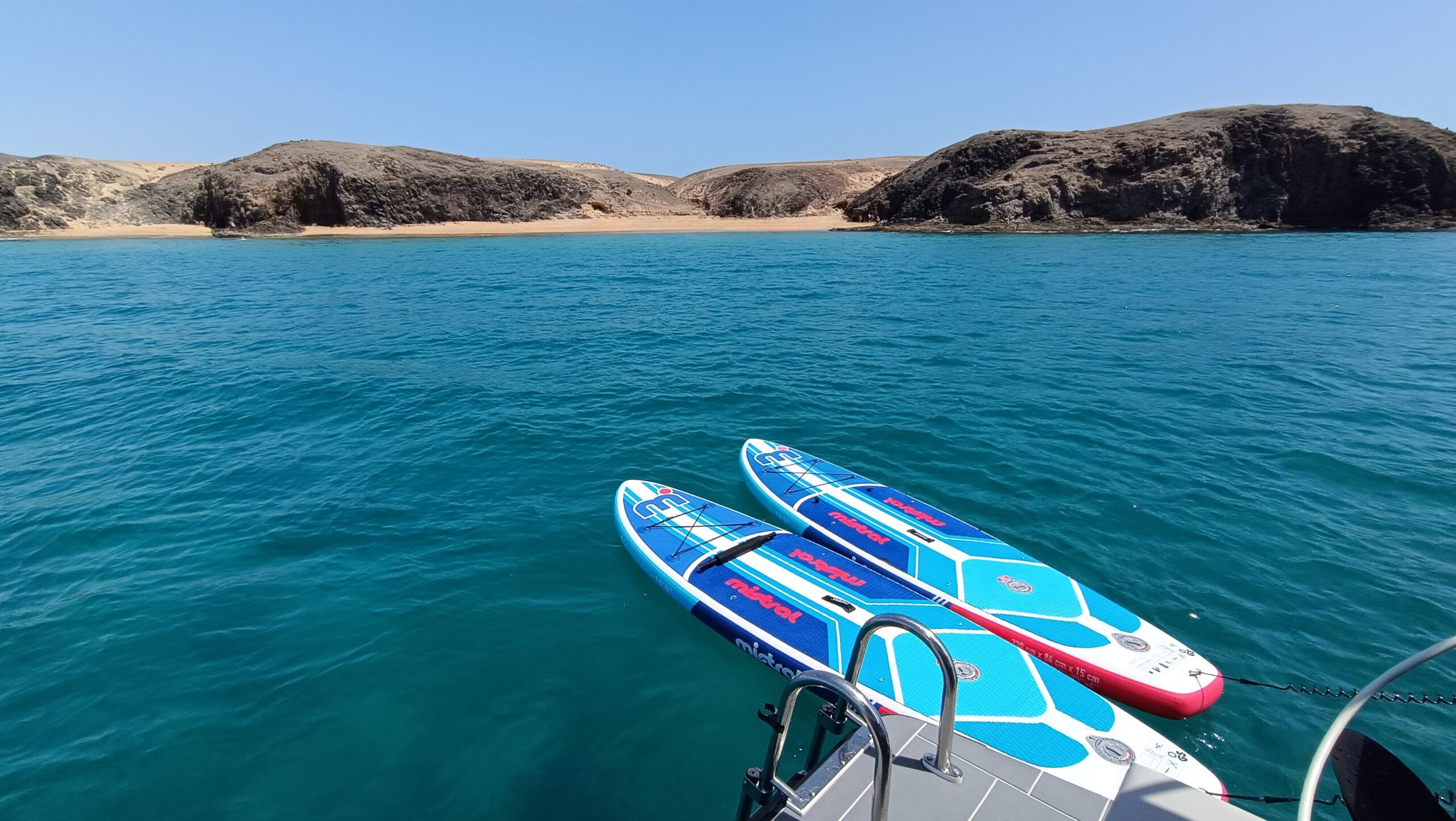 Bahía de Papagayo con aguas turquesas y tablas de paddle junto al yate.